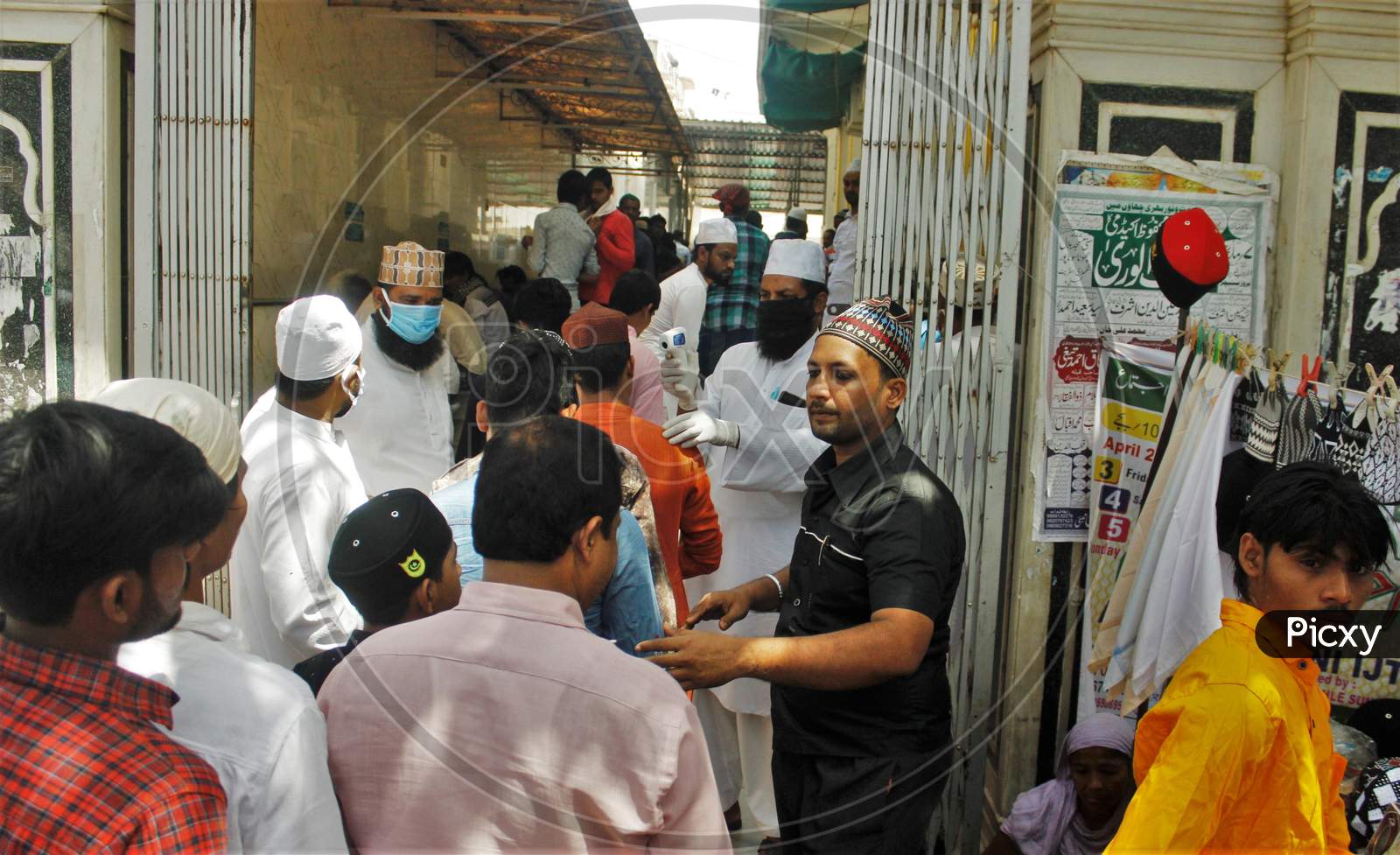 Devotees stand in a queue to gets themselves scanned with an infrared thermometer to check their temperatures as a precautionary measure against coronavirus disease (COVID-19), outside a mosque, in Mumbai, India on March 20, 2020.