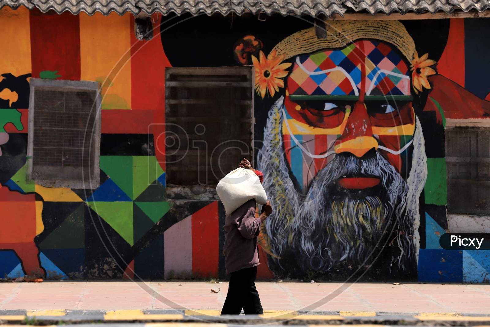 A Man walks past a mural On A Hot Weather day In Prayagraj, May 26, 2020.