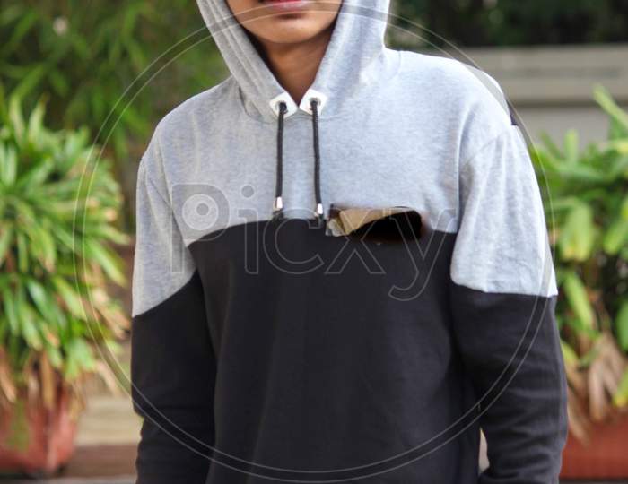 Young boy wearing hoodie and cap and posing for photo at a park