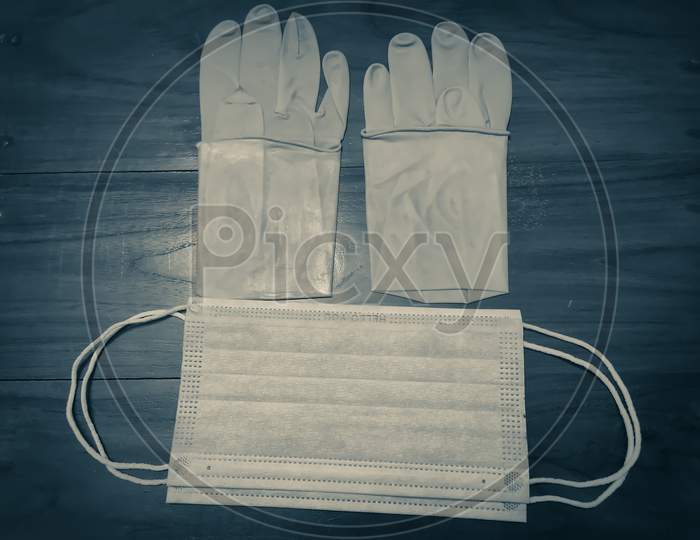 A Pair Of Rubber Medical Gloves, Surgical Mask On A Wooden Table.V