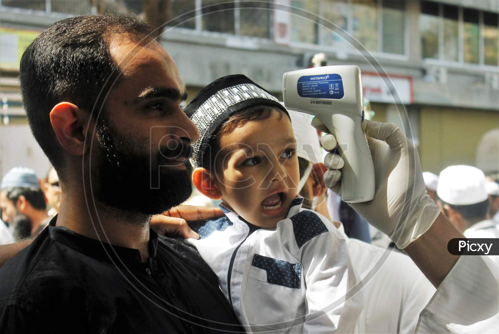 A kid reacts upon a devotee getting scanned with an infrared thermometer to check his temperature as a precautionary measure against coronavirus outside a mosque in Mumbai, India, March 20, 2020.