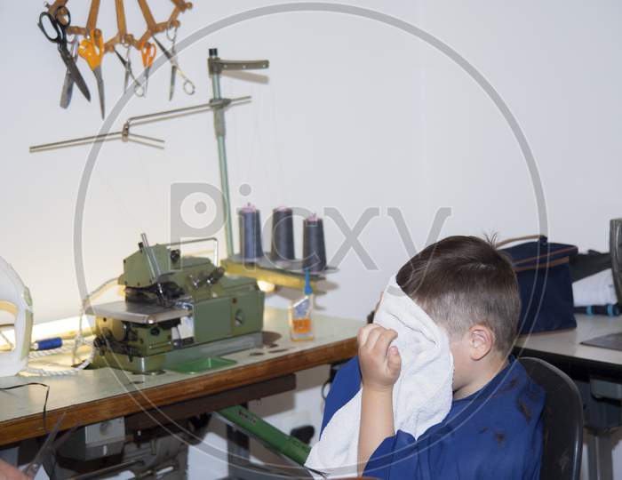 Boy Is Cleaning Face After A Haircut At Home In Home Sewing Room