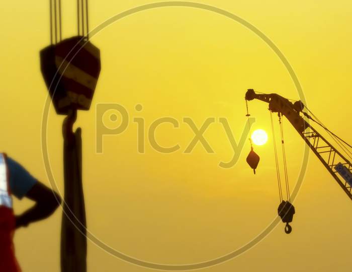 Dhaka,Bangladesh-January 21,2020 : Silhouette Of Construction Worker On Construction Site Beside Sunset Through A Crane.