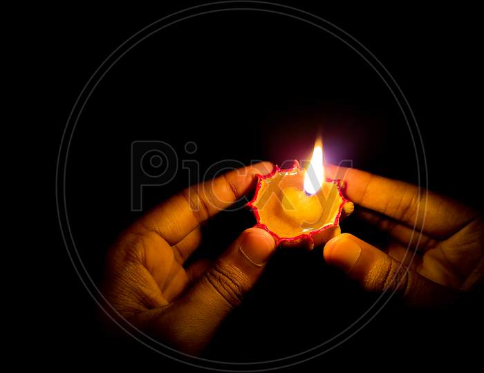 Happy diwali - Close up of man's hands holding oil lamp (diya) during diwali festival of lights
