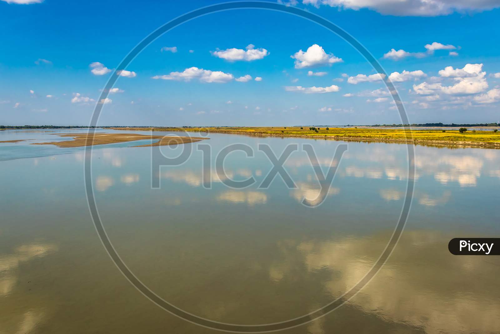 Clear Blue Sky With Many Small Cloud Patch And River Water Reflection
