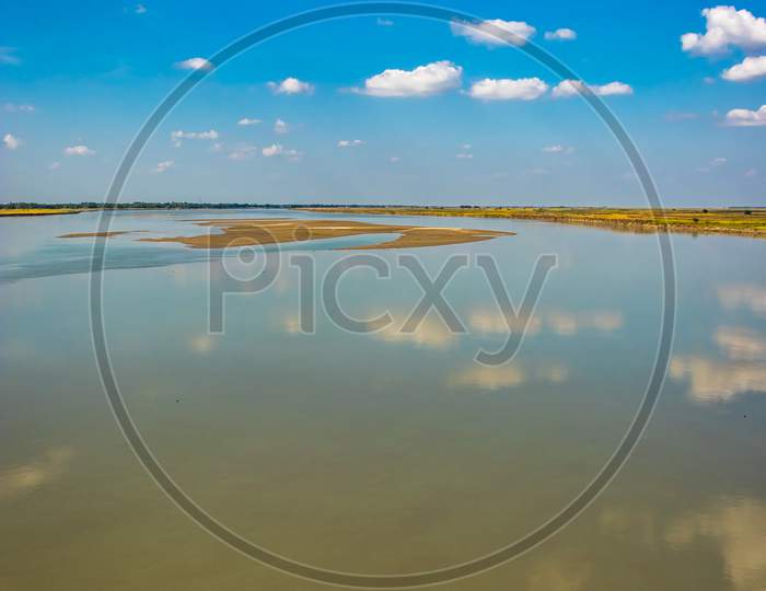 Clear Blue Sky With Many Small Cloud Patch And River Water Reflection