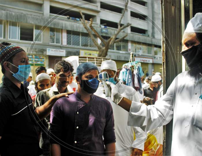 Devotees gets scanned with an infrared thermometer to check their temperature as a precautionary measure against coronavirus outside a mosque in Mumbai, India, March 20, 2020.