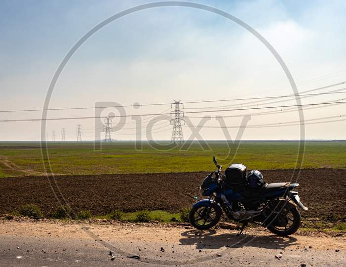 Electricity Pole With High Tension Power Transmission Cable With Motorcycle Parked On Road