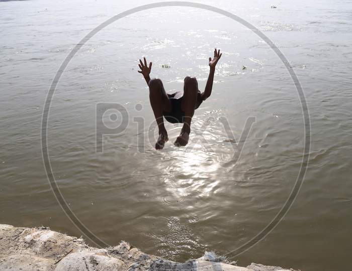 A Boy Jumps In The River Ganga To Beat The Heat On A Hot Summer Day During A Nationwide Lockdown amidst Coronavirus Disease (Covid-19), In Prayagraj, May 26, 2020.