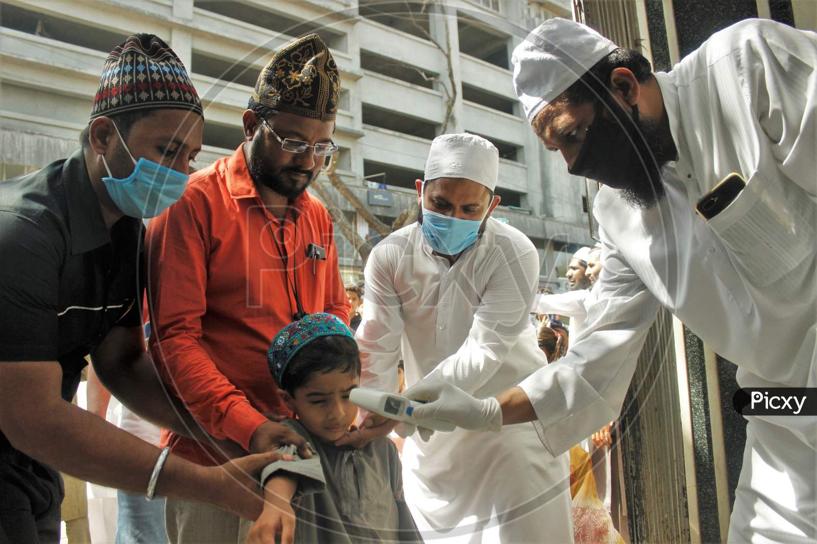 A kid gets scanned with an infrared thermometer to check his temperature as a precautionary measure against coronavirus outside a mosque in Mumbai, India, March 20, 2020.