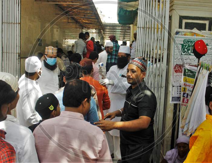 Devotees stand in a queue to gets themselves scanned with an infrared thermometer to check their temperatures as a precautionary measure against coronavirus disease (COVID-19), outside a mosque, in Mumbai, India on March 20, 2020.