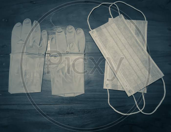 A Pair Of Rubber Medical Gloves, Surgical Mask And On A Wooden Table.V