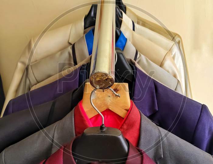 Men multi colored blazers hanging inside a shop .Closeup of gray man's suit with others hanging on hangers in tailor shop.Shop jacket men series, business hanger clothing. blazers for Men in wedding