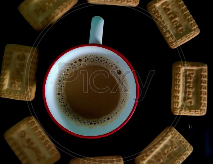 A cup of tea and biscuits with black background