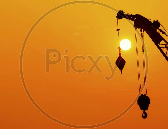 Silhouette Industrial Hook Crane In Sunset Background. Silhouette Industrial Hook Crane In Sunset Time.
