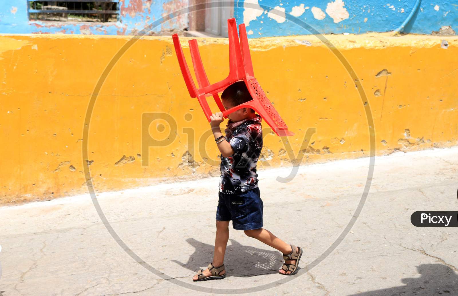 A Boy Holds a Chair To Beat The Heat On A Hot Day During extended Nationwide Lockdown amidst  Coronavirus or COVID-19 Pandemic  In Prayagraj, May 27, 2020.