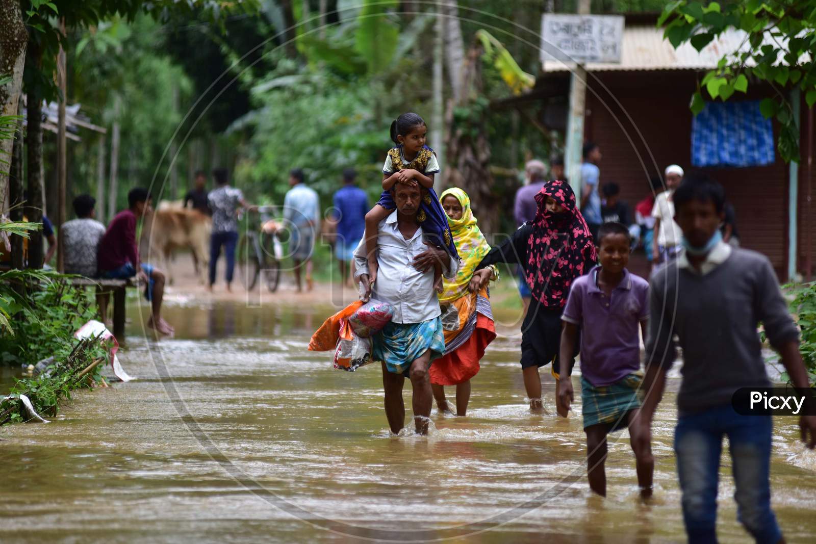 A Man Carries His Daughter As He  Wades Through A Flooded Area To Reach A Safer Place At Flood Affected  At  Bakulguri Village Near Kampur In Nagaon District Of Assam On May 27,2020.