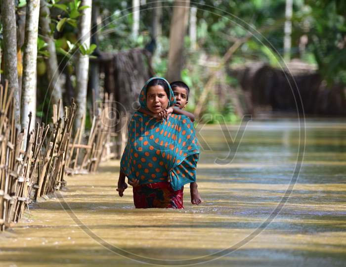 A Women Carries Her Child  As She  Wades Through A Flooded Area To Reach A Safer Place At  Bakulguri Village Near Kampur In Nagaon District Of Assam On May 27,2020.