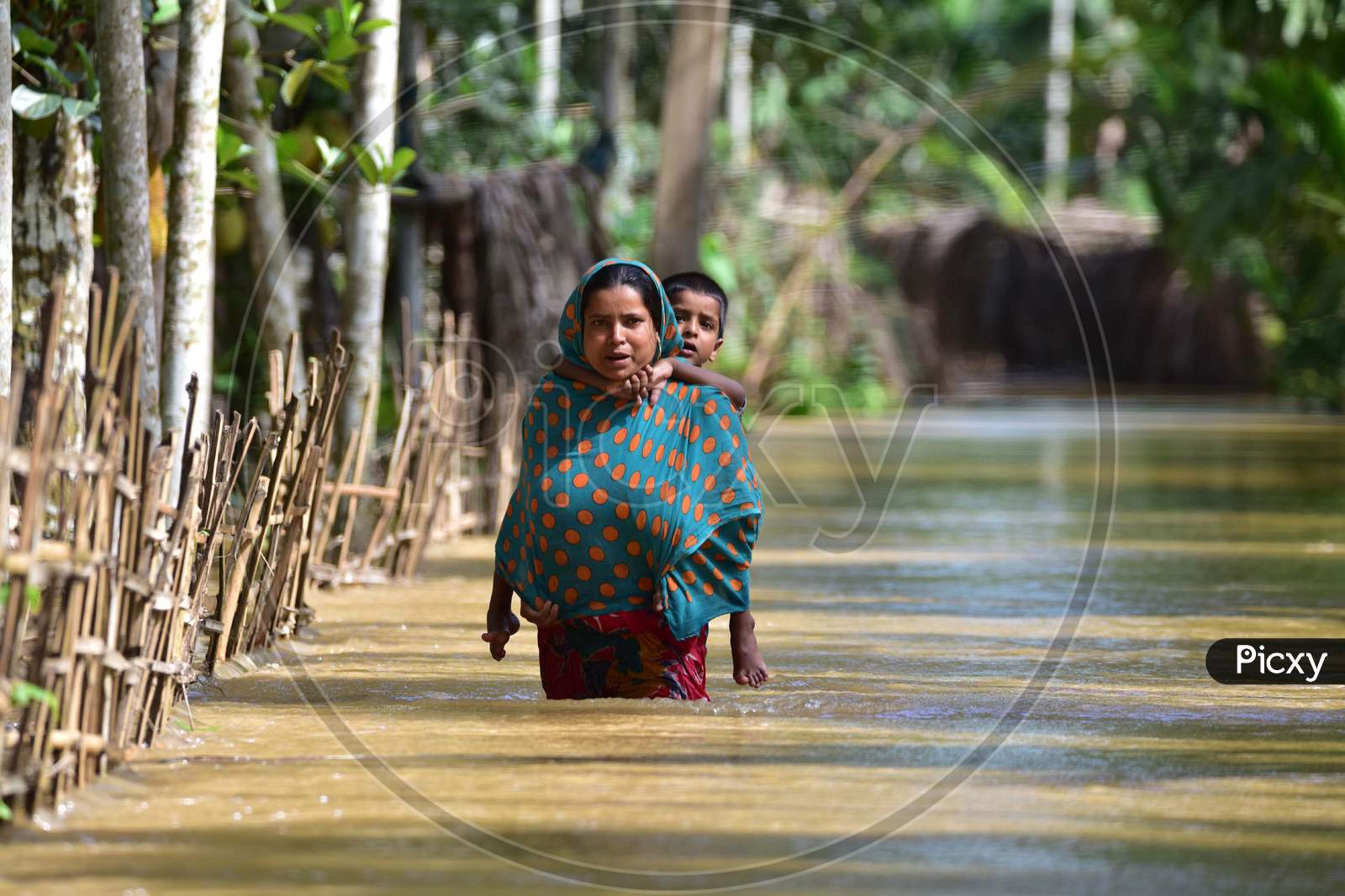 A Women Carries Her Child  As She  Wades Through A Flooded Area To Reach A Safer Place At  Bakulguri Village Near Kampur In Nagaon District Of Assam On May 27,2020.