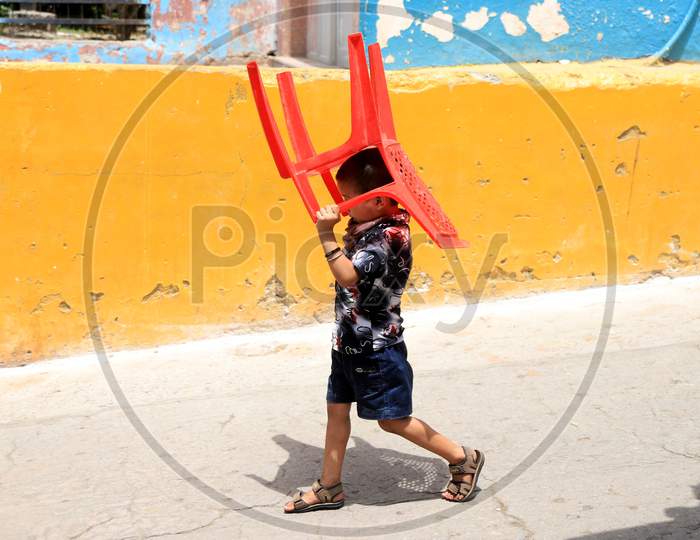 A Boy Holds a Chair To Beat The Heat On A Hot Day During extended Nationwide Lockdown amidst  Coronavirus or COVID-19 Pandemic  In Prayagraj, May 27, 2020.