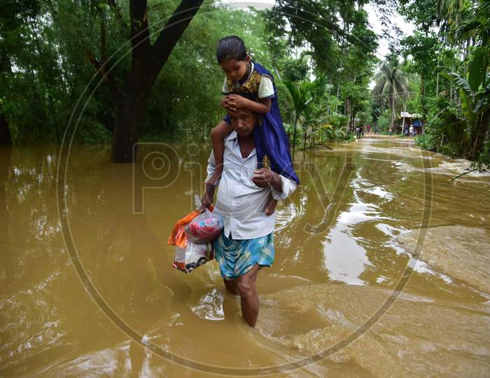 A Man Carries His Daughter As He  Wades Through A Flooded Area To Reach A  Safer Place  At  Bakulguri Village Near Kampur In Nagaon District Of Assam On May 27,2020.