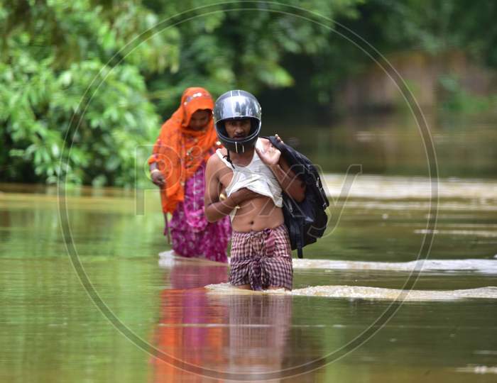 Villagers Wade Through A Flooded Area To Reach A Safer Place At  Bakulguri Village Near Kampur In Nagaon District Of Assam On May 27,2020.