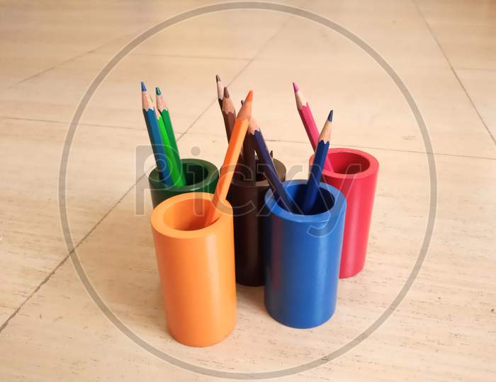 Colourful wooden stationery holder with colourful pencils in it.