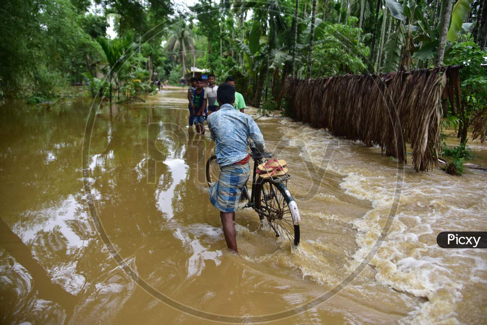 A Man Pushes His Bicycle Through Flooded Water At  Bakulguri Village Near Kampur In Nagaon District Of Assam On May 27,2020.