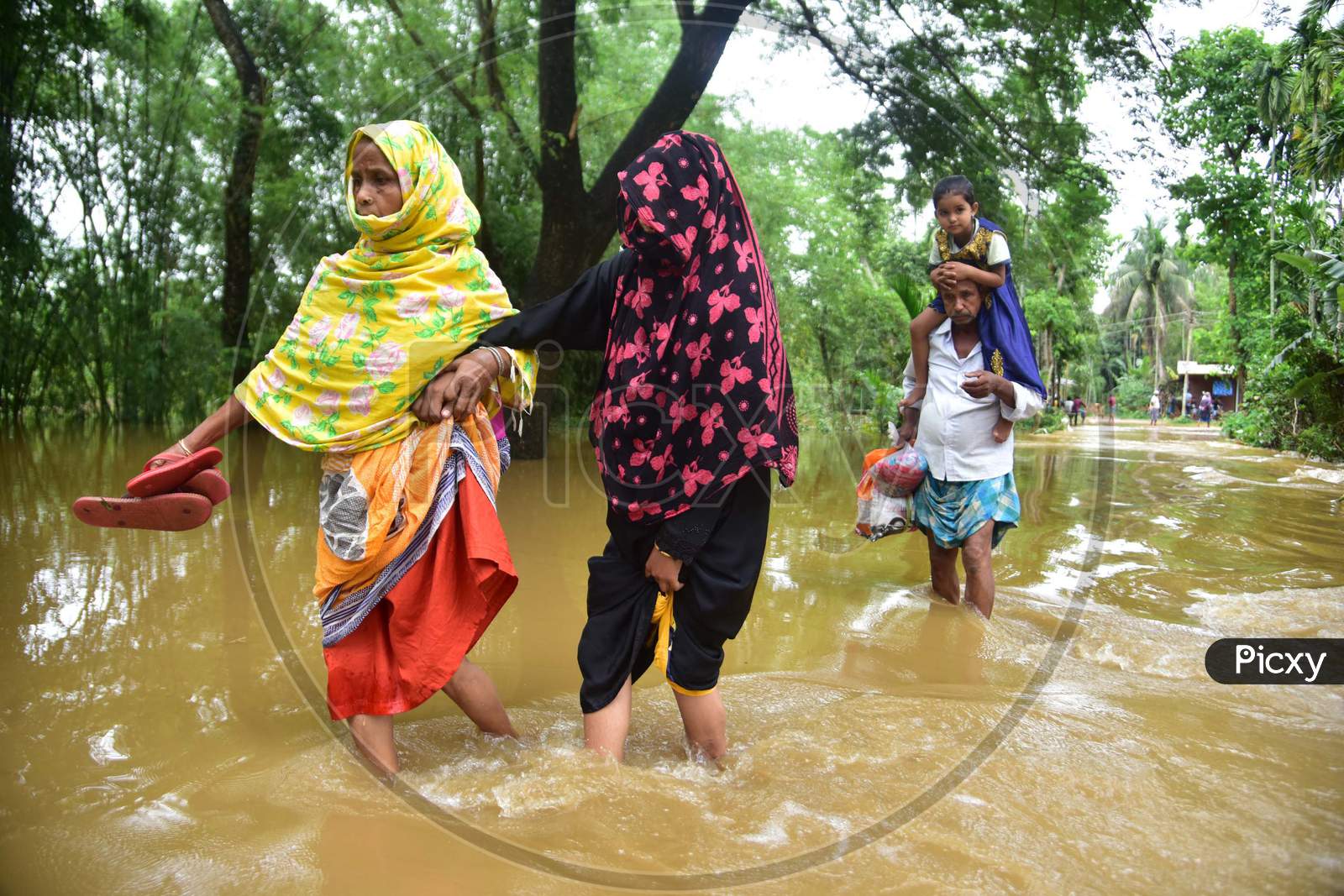 Villagers Wade Through A Flooded Area To Reach A  Safer Place At  Bakulguri Village Near Kampur In Nagaon District Of Assam On May 27,2020