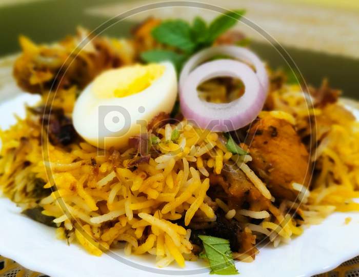 Chicken biryani garnishing with an egg and onion rings