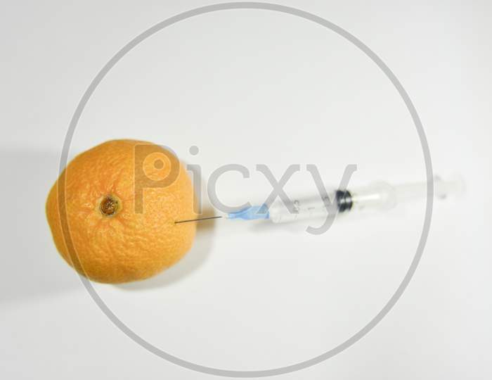 Unfocused Syringe Injecting Orange. Gmo And Laboratory Studies Concept