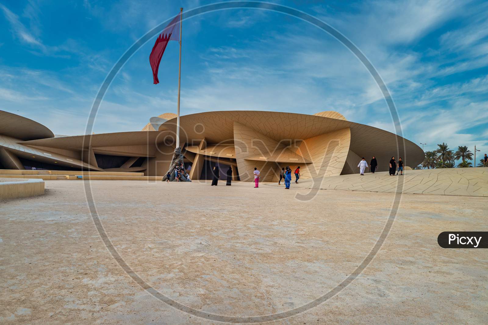 National Museum of Qatar (Desert rose) exterior  daylight view with  Qatar flag and clouds in sky