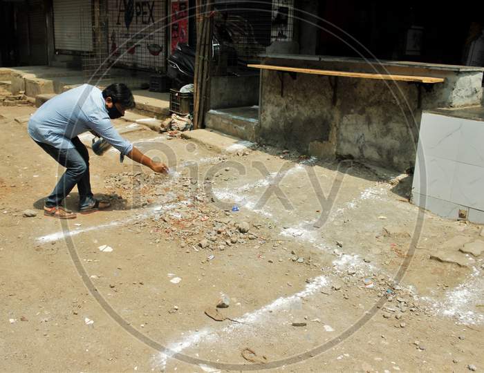 A man uses powder to make lines to mark positions for maintaining physical distance at a market place to limit the spread of the coronavirus disease (COVID-19) , in Mumbai, India on March 28, 2020.