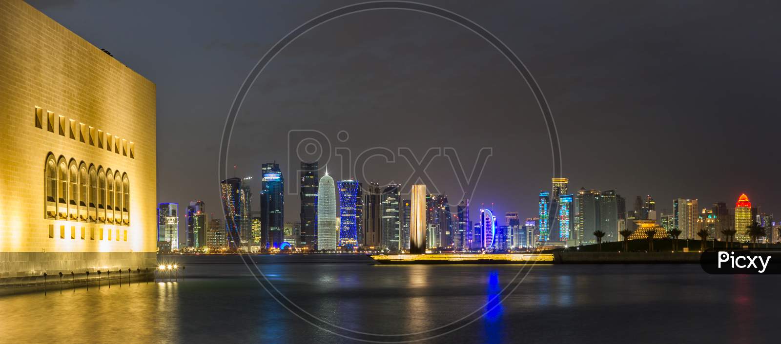Doha Qatar skyline at night showing skyscrapers lights reflected in the Arabic gulf