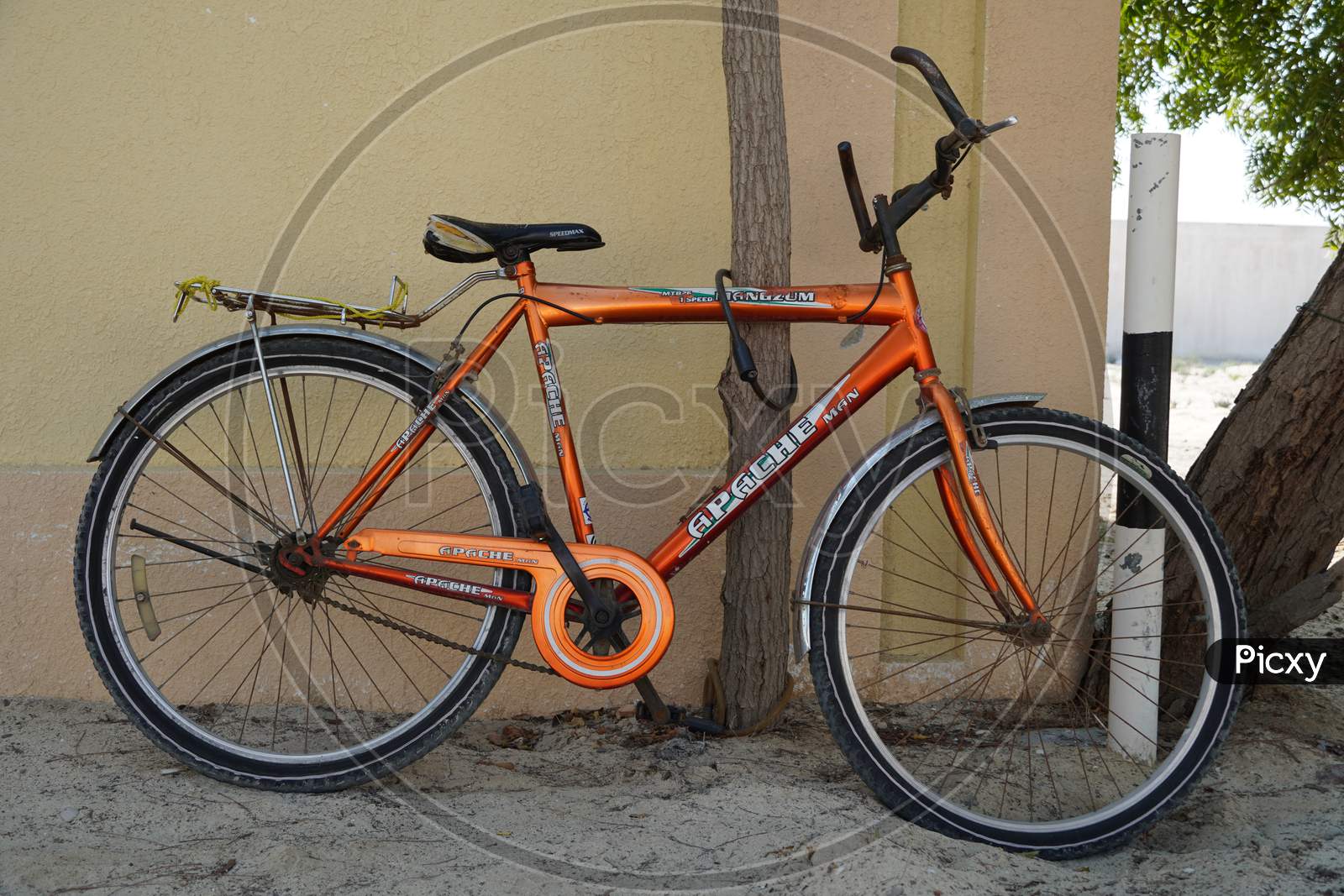 Image of An Old Orange Bicycle Is Standing On The Sand Path Locked