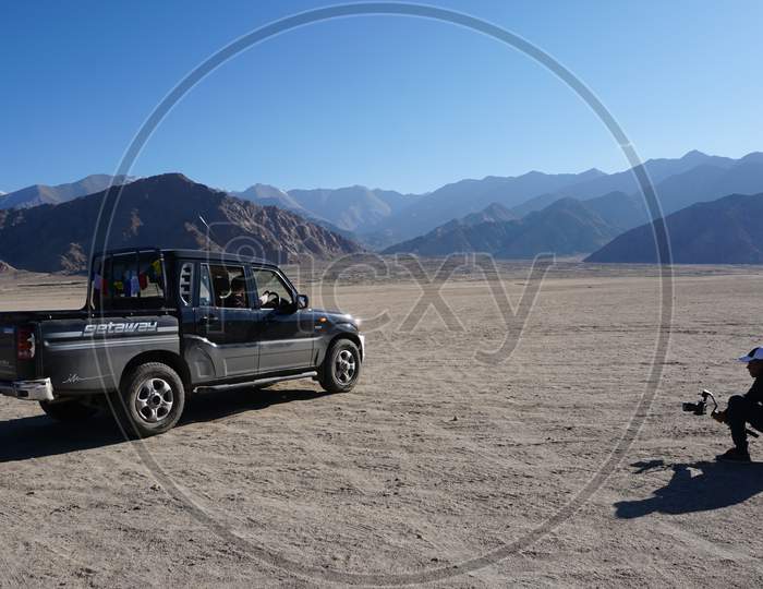 Man Clicking Picture Of A Jeep In Leh Mountains