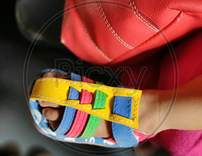 Baby foot wearing colourful shoe.
