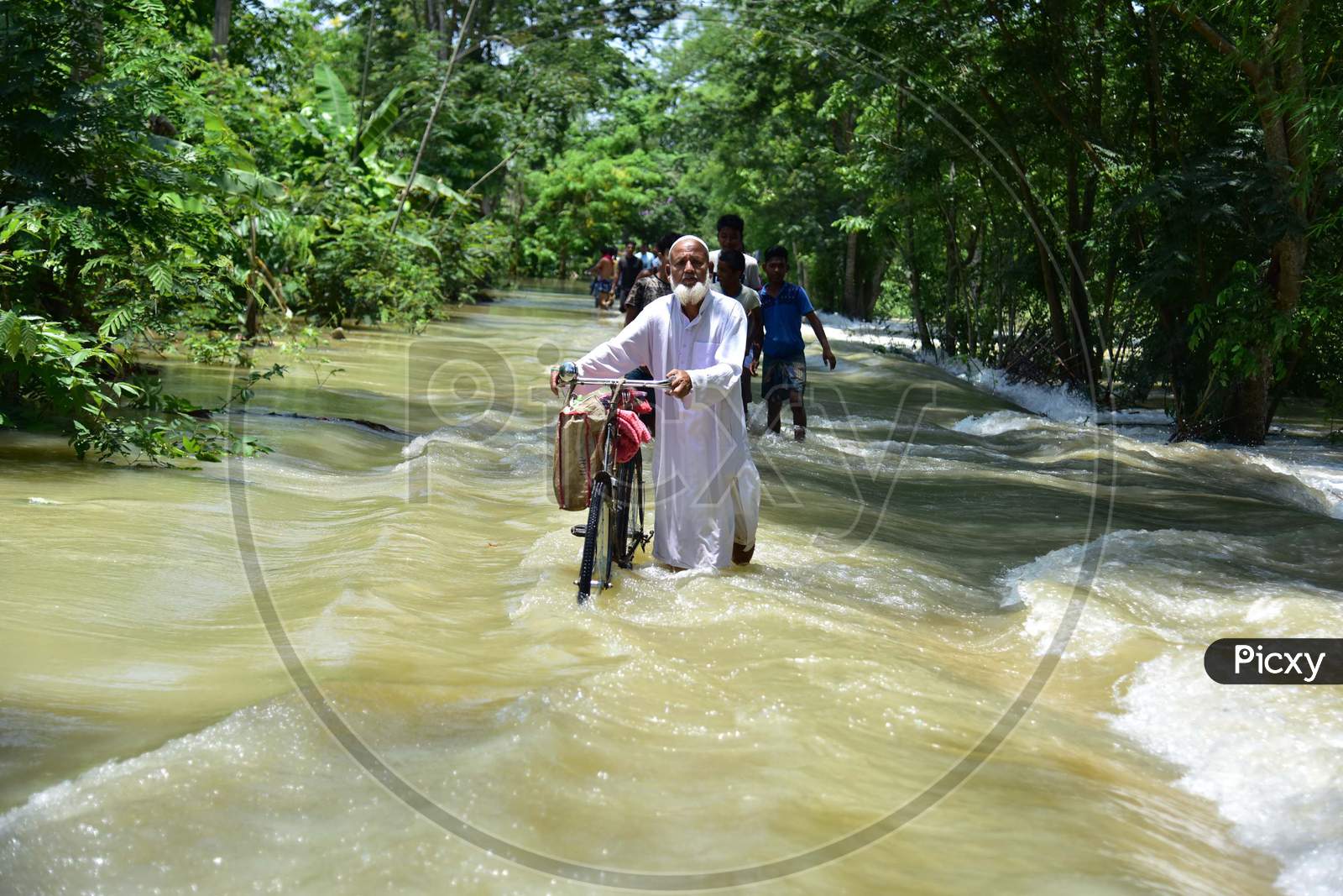 A Man Pushes His Bicycle Through A Flood Water At Doboka  In  Hojai  District Of Assam  On May 28,2020.