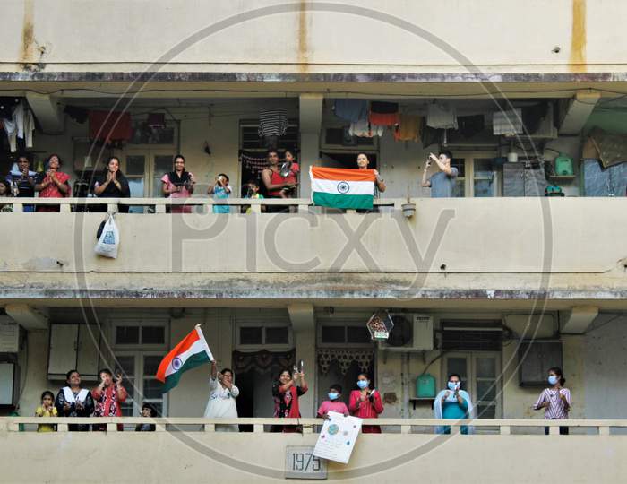 People clap and bang utensils from their balconies to cheer for emergency personnel and sanitation workers who are on the frontlines in the fight against coronavirus, in Mumbai, India on March 22, 2020.
