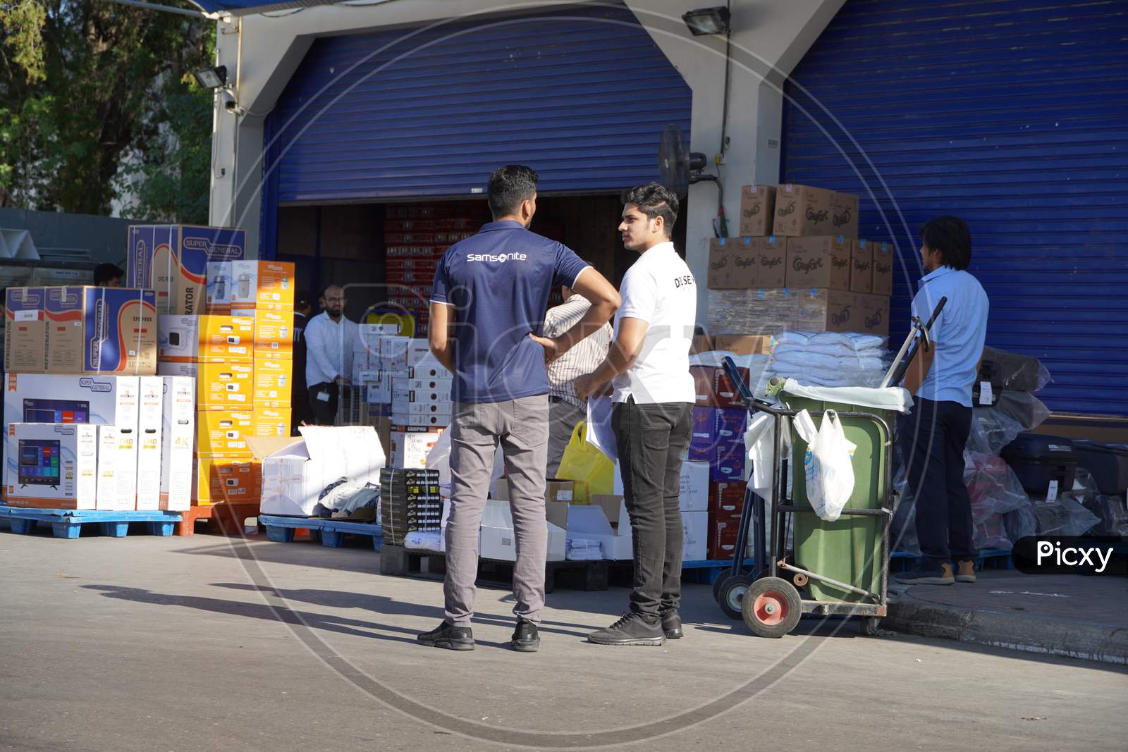 Workers With Manual Forklift And Boxes Stockpile Goods Near Storage Room In Wholesale Shop. Back Side Of Supermarket. Unloading Dock For Goods At Storehouse. Logistics Center.- Dubai Uae December 2019
