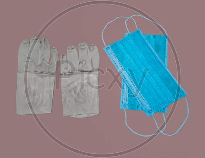 A Pair Of Rubber Medical Gloves And Surgical Mask Isolated On gray Background