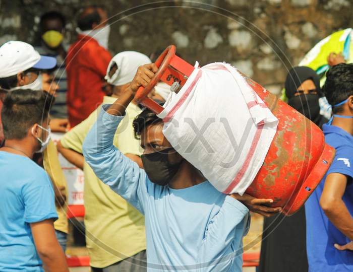 A man carries a gas cylinder as people wait to purchase cooking gas after India ordered a 21- day nationwide lockdown to limit the spreading of coronavirus disease (COVID-19) in Mumbai, India March 27, 2020.