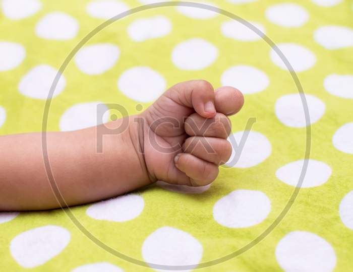 Closed Fist Of An Infant On Polka Dots