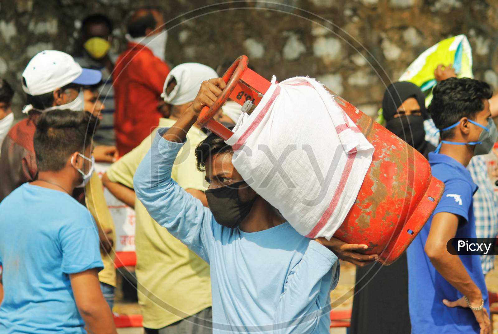 A man carries a gas cylinder as people wait to purchase cooking gas after India ordered a 21- day nationwide lockdown to limit the spreading of coronavirus disease (COVID-19) in Mumbai, India March 27, 2020.