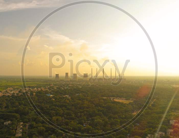 Aerial View Of Coal Power Plant -Smoke From Factory Chimnys - Sunrise At Green Covered City With Factories Outside The City, Raichur, India
