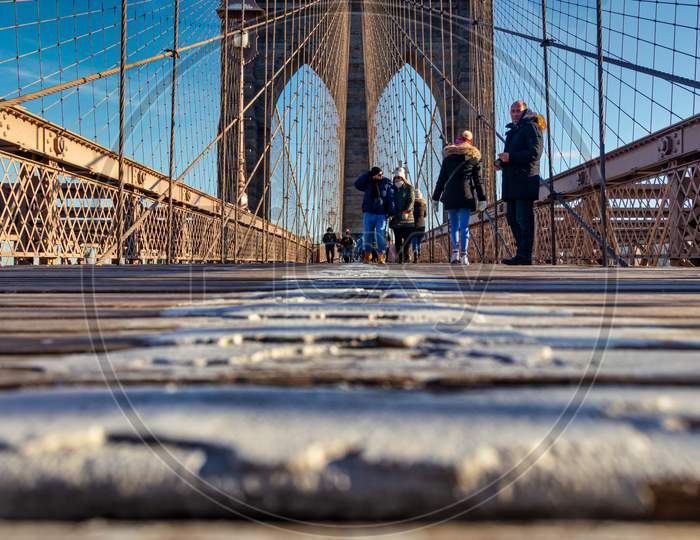 Brooklyn Bridge daylight view low angle shot with people walking on the bridge and clouds in sky in background
