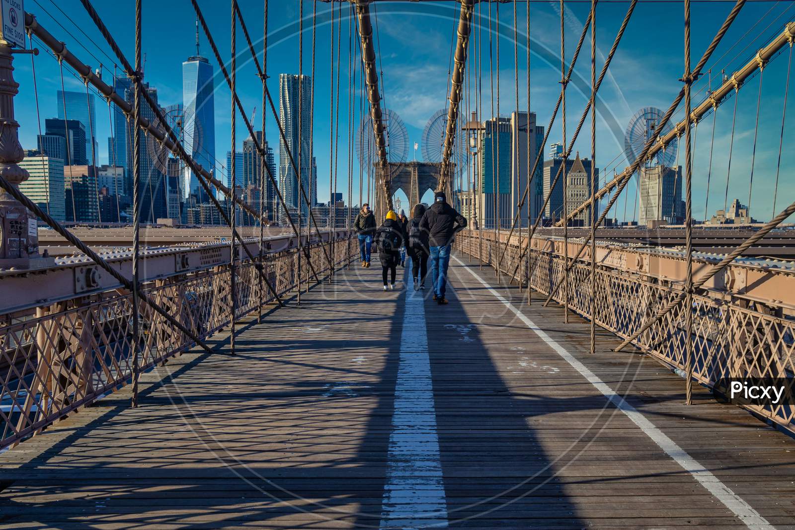 Brooklyn Bridge daylight view with people walking on the bridge ,skyline and clouds in sky in background
