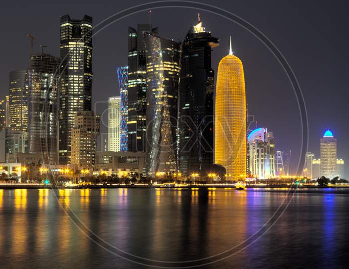 Doha Qatar skyline at night showing skyscrapers lights reflected in the Arabic gulf
