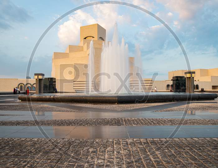 Museum of Islamic Art , Doha,Qatar in daylight exterior view with fountain in the foreground and clouds in the sky in the background