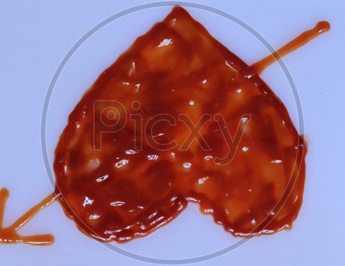 Ketchup in a shape of heart on white background